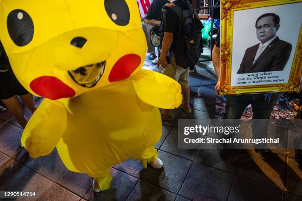 Man carries a mock funeral portrait of Thailand's Prime Minister Prayuth Chan-O-Cha, while another person dances in a "Pikachu" costume on December...