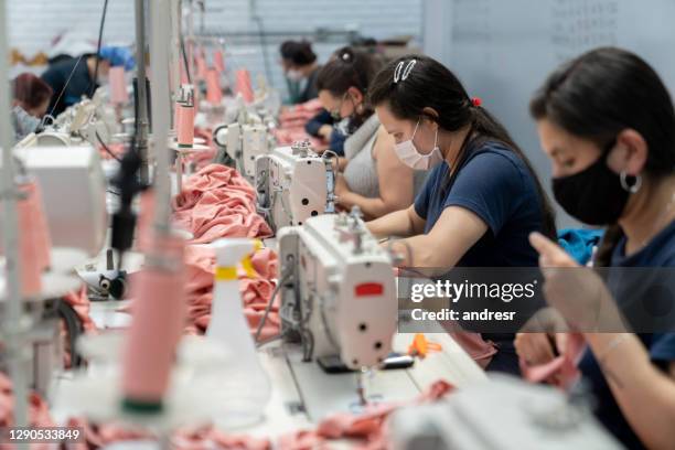 mujeres que trabajan en una fábrica textil con máscara facial mientras cosen ropa - fábrica textil fotografías e imágenes de stock