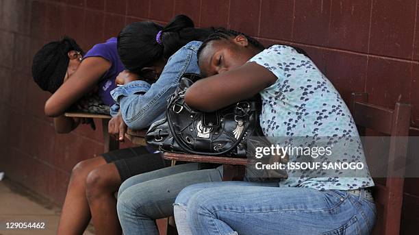 Three women sleep outside a polling station in Monrovia on October 12, 2011 after spending the night waiting for results, a day after Liberia's...