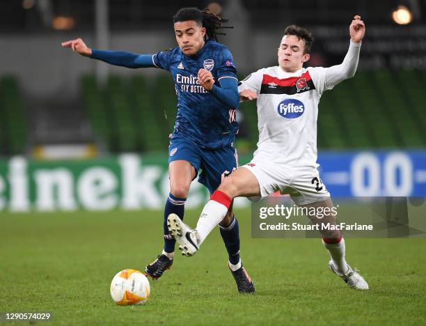 Miguel Azeez of Arsenal breaks past James Wynne of Dundak during the UEFA Europa League Group B stage match between Dundalk FC and Arsenal FC at...