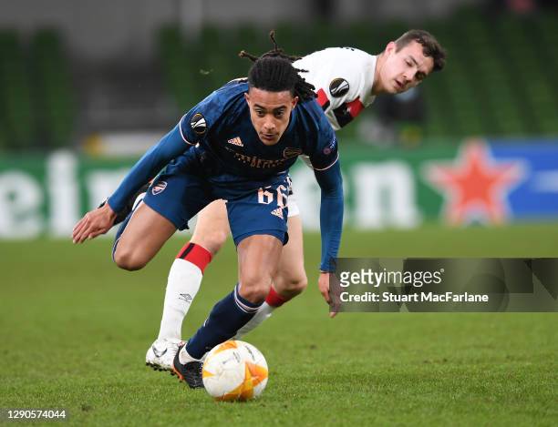 Miguel Azeez of Arsenal breaks past James Wynne of Dundak during the UEFA Europa League Group B stage match between Dundalk FC and Arsenal FC at...