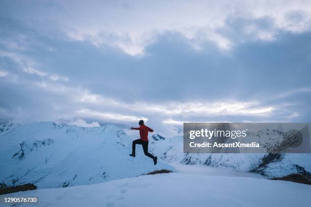 young man trail jumps down snowy mountain slope in the morning - leap of faith activity stock pictures, royalty-free photos & images