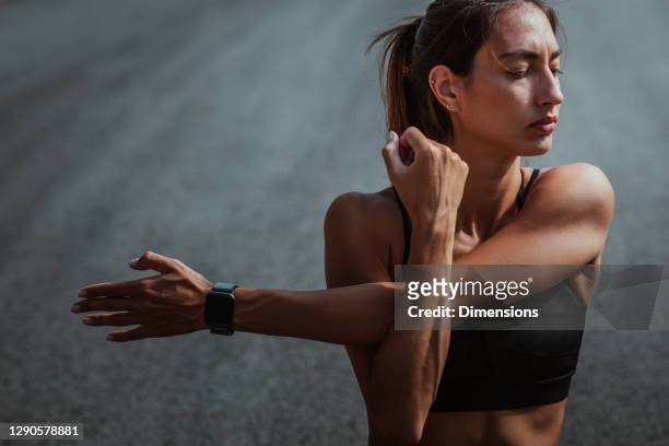 female stretching after jogging while sitting on the road - muscular build stock pictures, royalty-free photos & images