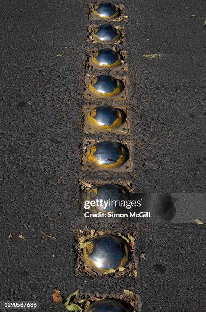 row of stainless steel speed bumps on a bitumen road - bumpy stockfoto's en -beelden