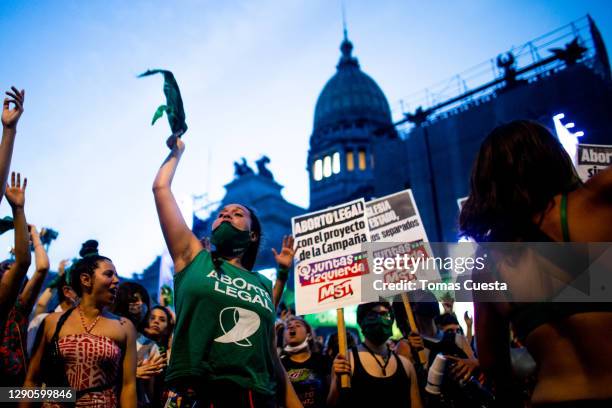 Pro-choice activist waves a green kerchief while others shout slogans outside the National Congress as Deputies vote on a bill to legalize abortion...