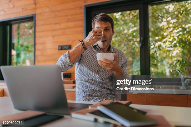 handsome man eating while working - telecommuting eating stock pictures, royalty-free photos & images