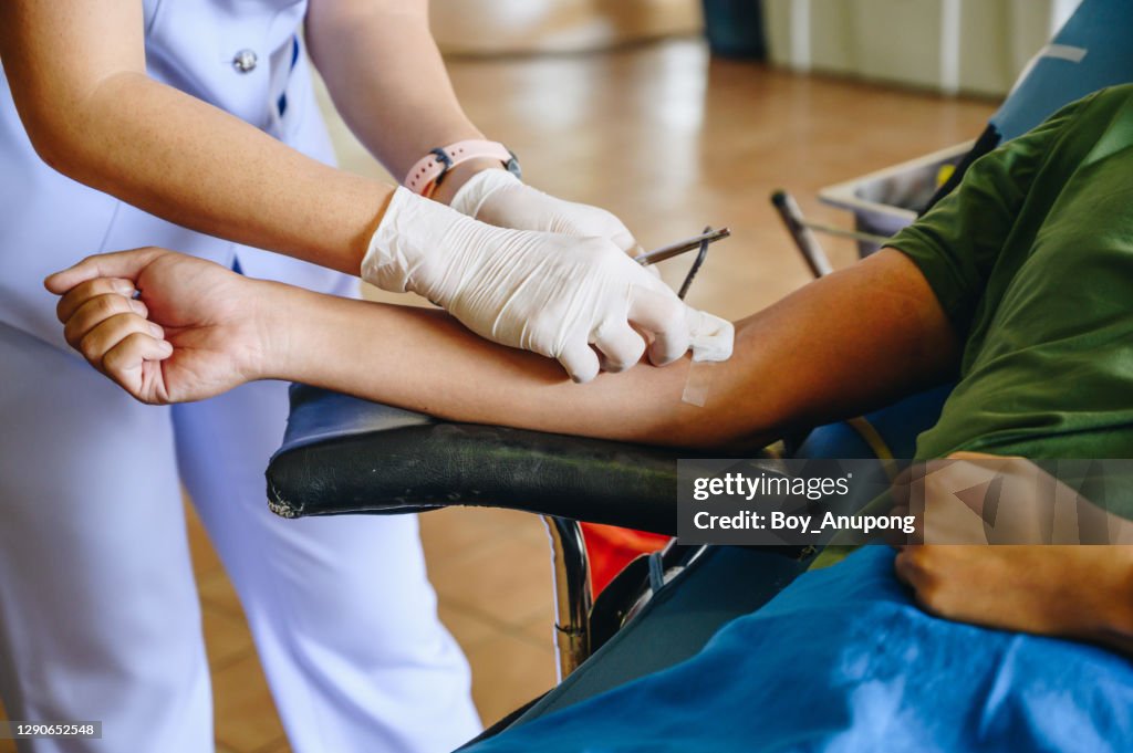 Nurse help patient to stop bleeding while donating blood.