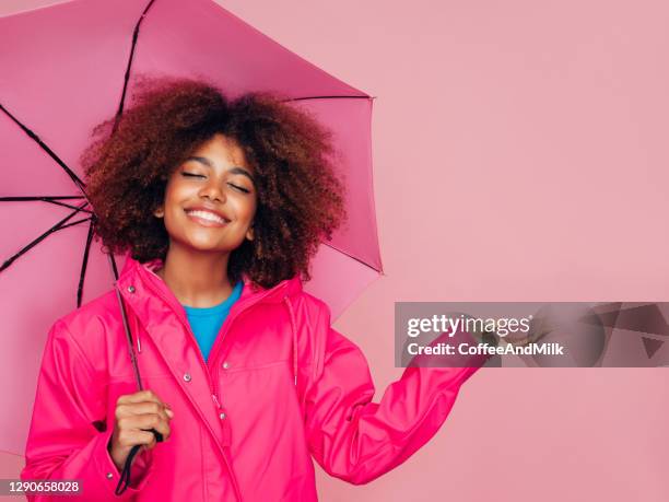 afro-mädchen mit rosa regenschirm - african american women wet stock-fotos und bilder