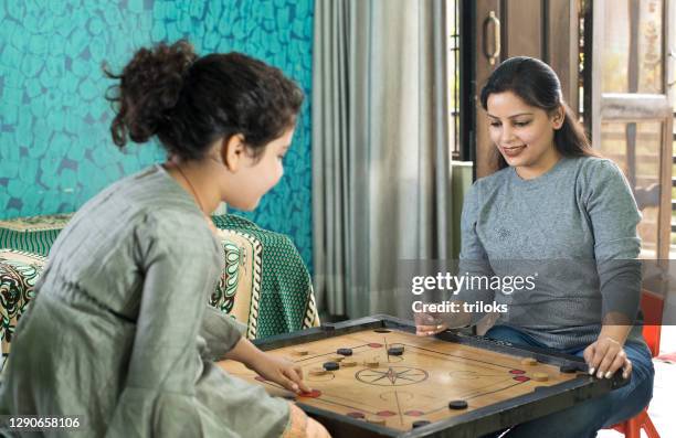 loving mother and daughter playing carrom at home - carrom board stock pictures, royalty-free photos & images