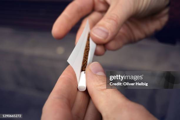 close-up of hands rolling a cigarette - roll up stockfoto's en -beelden