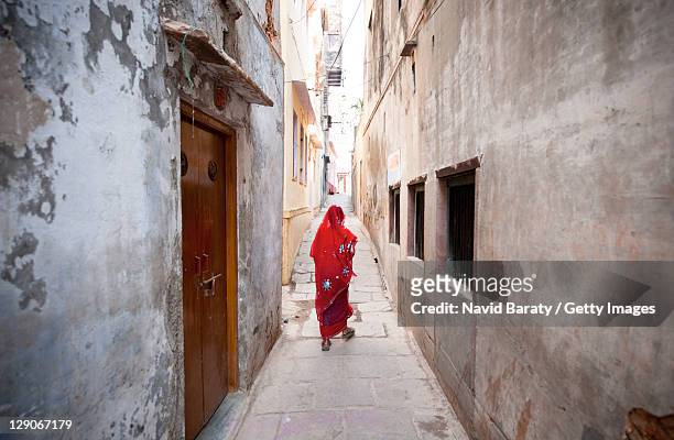 woman walking on alley - woman in red sari stock-fotos und bilder