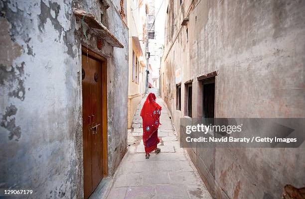 woman walking on alley - woman in red sari stock pictures, royalty-free photos & images