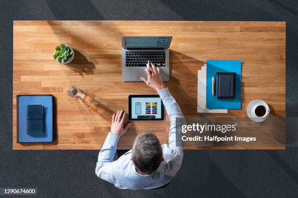 top view of businessman working at desk, using laptop and tablet. - draufsicht büro stock-fotos und bilder