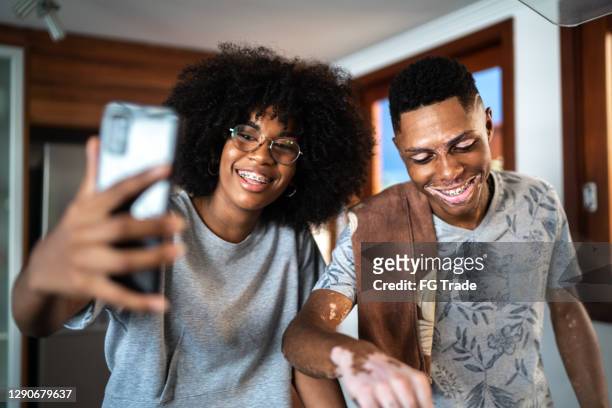 young couple or siblings doing a video call while cooking at home - selfie male stock pictures, royalty-free photos & images