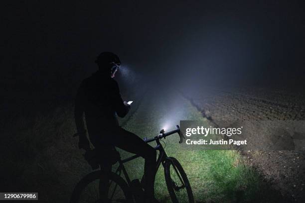 cyclist checking for directions on smartphone whilst out in the countryside on a dark foggy evening - remote location cell phone stock pictures, royalty-free photos & images