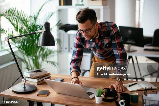 jonge zakenman die in het bureau werkt - bureaulamp stockfoto's en -beelden