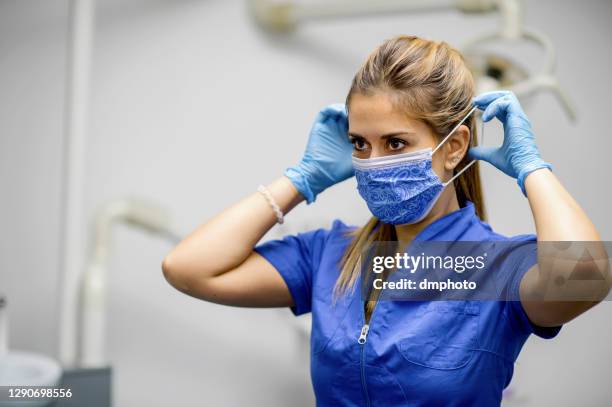 female health care worker putting mask on - putting gloves stock pictures, royalty-free photos & images