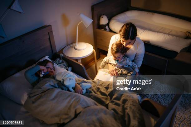 madre leyendo un libro a sus dos hijos - bedtime fotografías e imágenes de stock