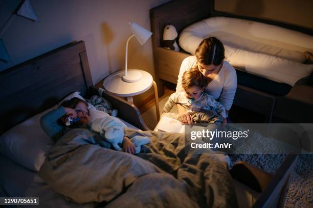 mother reading a book to her two sons - conto-de-fadas imagens e fotografias de stock