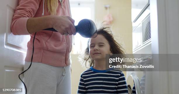 mother blow cold air with a hair dryer to her three year old son - 40 year old male face stockfoto's en -beelden