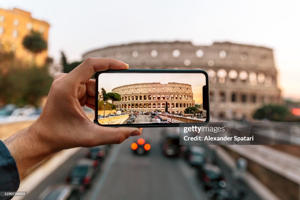 Tourist photographing Coliseum with smartphone, Rome, Italy
