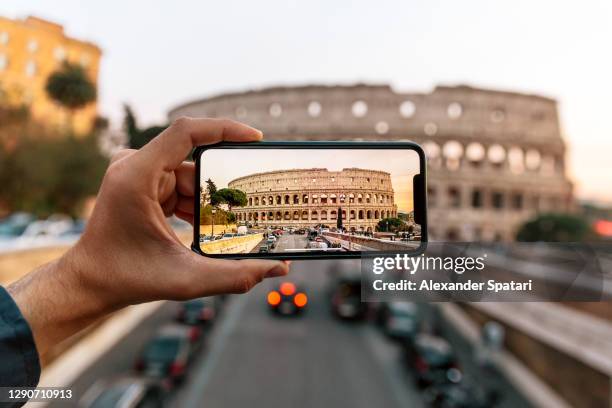 tourist photographing coliseum with smartphone, rome, italy - vue subjective main photos et images de collection
