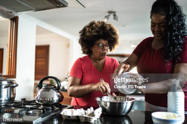 mother and daughter baking cake together at home - granddaughter stock pictures, royalty-free photos & images