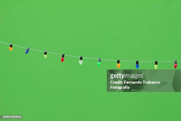 colored light bulbs on green background - hanging christmas lights stock-fotos und bilder