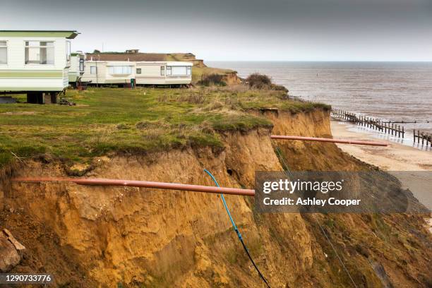 drainage pipes from caravan plots that have fallen into the sea at happisburgh, one of the fastest eroding parts of the norfolk coast , where several houses have been lost to the sea. - caravan uk stock-fotos und bilder