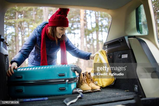 glückliche junge frau packt ihren koffer, um in einen wanderurlaub zu gehen - luggage trunk stock-fotos und bilder