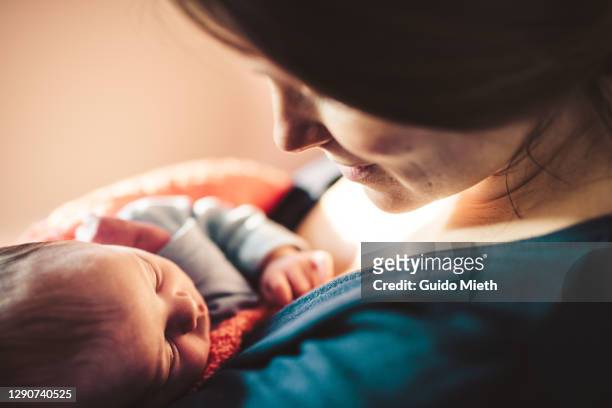 smiling mother looking at her newborn baby daughter. - neu stock-fotos und bilder