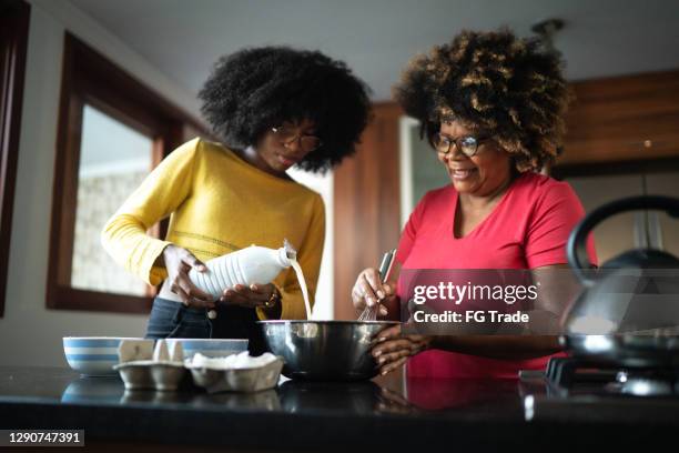 mother and daughter making cake together - afro friends home stock pictures, royalty-free photos & images