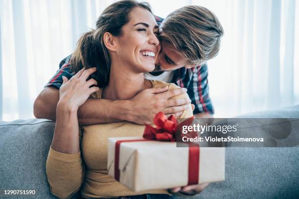 joven alegre recibiendo un regalo de su novio. - dar fotografías e imágenes de stock