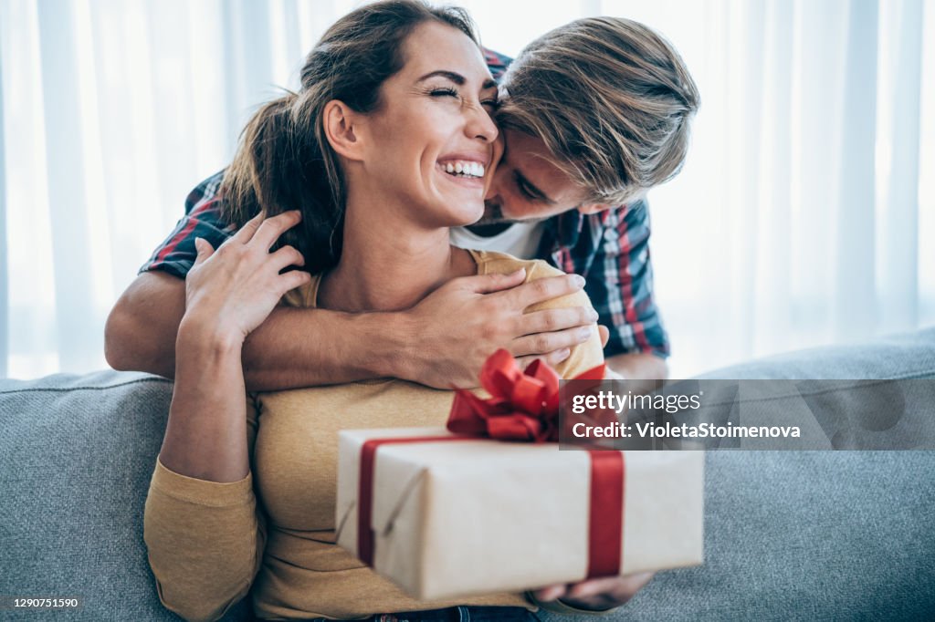 Jeune femme gaie recevant un cadeau de son petit ami.