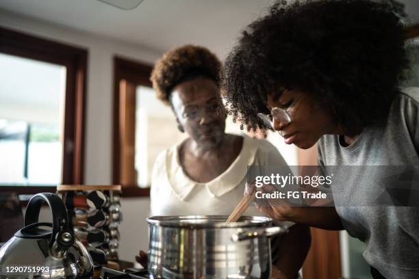 hija y madre cocinando juntos en casa - black cook fotografías e imágenes de stock