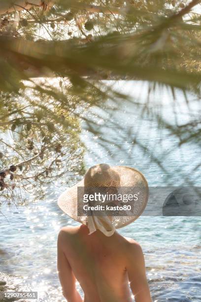 rear view of woman wearing hat standing by lake - einzelne frau über 30 stock-fotos und bilder