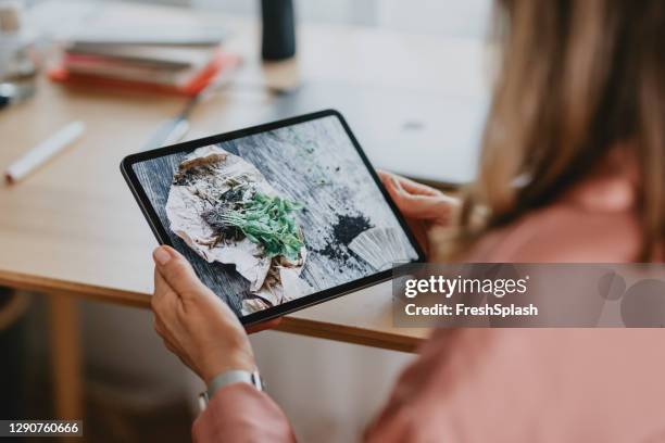 anonieme vrouw kijken naar een tutorial over hoe basilicum plant op haar digitale tablet - tutorial stockfoto's en -beelden