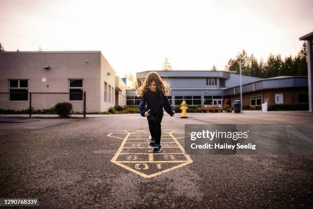 young girl plays hopscotch on a playground - hopscotch stock pictures, royalty-free photos & images