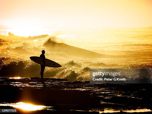 surfer holding surfboard on rocks - newcastle australia stock pictures, royalty-free photos & images