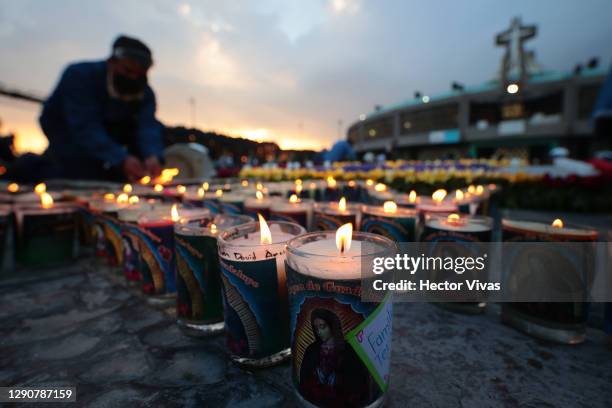 Staffer of the Basilica of Guadalupe lights candles with messages placed by Catholics in the days prior to the celebration in the central area of the...