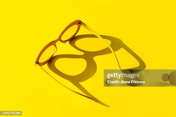 yellow glasses with shadow in sunlight. trendy colors of the year - sunglasses without people stock-fotos und bilder