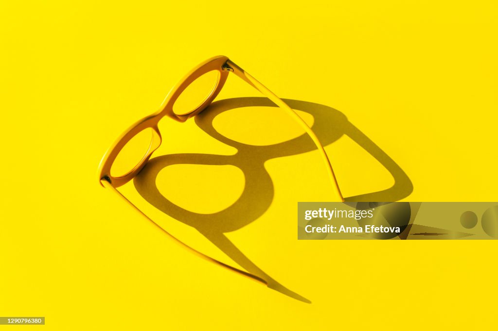 Yellow glasses with shadow in sunlight. Trendy colors of the year