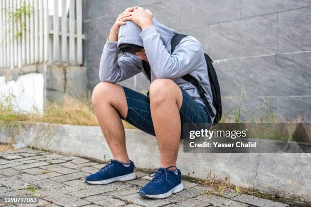 teenage boy sitting looking sad - hoodie boy stock pictures, royalty-free photos & images