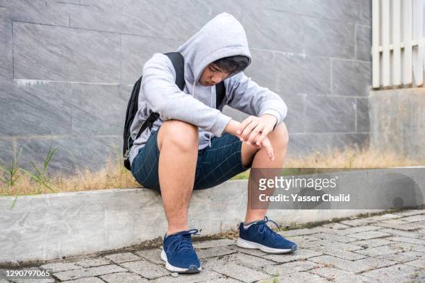 teenage boy sitting looking sad - teen boy shorts imagens e fotografias de stock