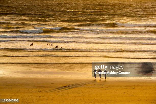 surfers at polzeath at sunset, cornwall, uk. - polzeath bildbanksfoton och bilder