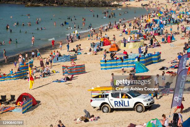 holiday makers on the beach in st ives, cornwall, uk. - beach shelter stockfoto's en -beelden