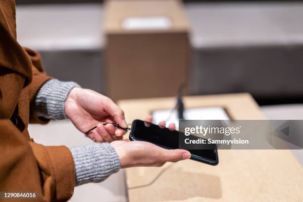 midsection of woman plugging in mobile charging - powerbank stock-fotos und bilder