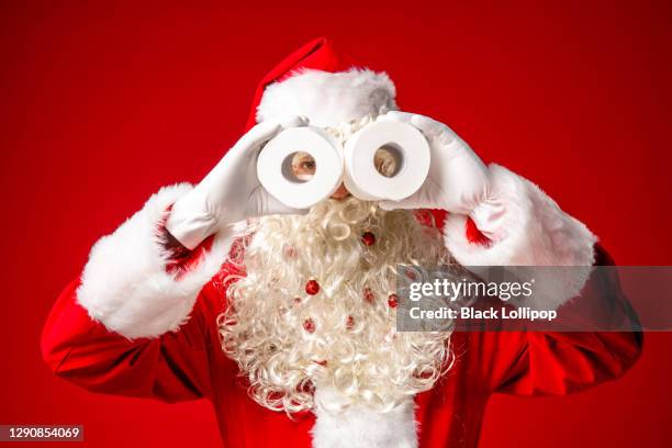 funny santa claus using toilet paper as binoculars looking to the camera.. - toilet paper stock pictures, royalty-free photos & images