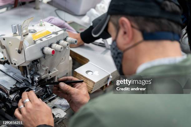 man working at a textile factory doing maintenance on a sewing machine - sewing machine stock pictures, royalty-free photos & images