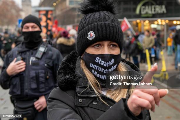 Woman discusses with a police officer in front of a water cannon while opponents of what they claim are restrictions to their personal freedoms due...